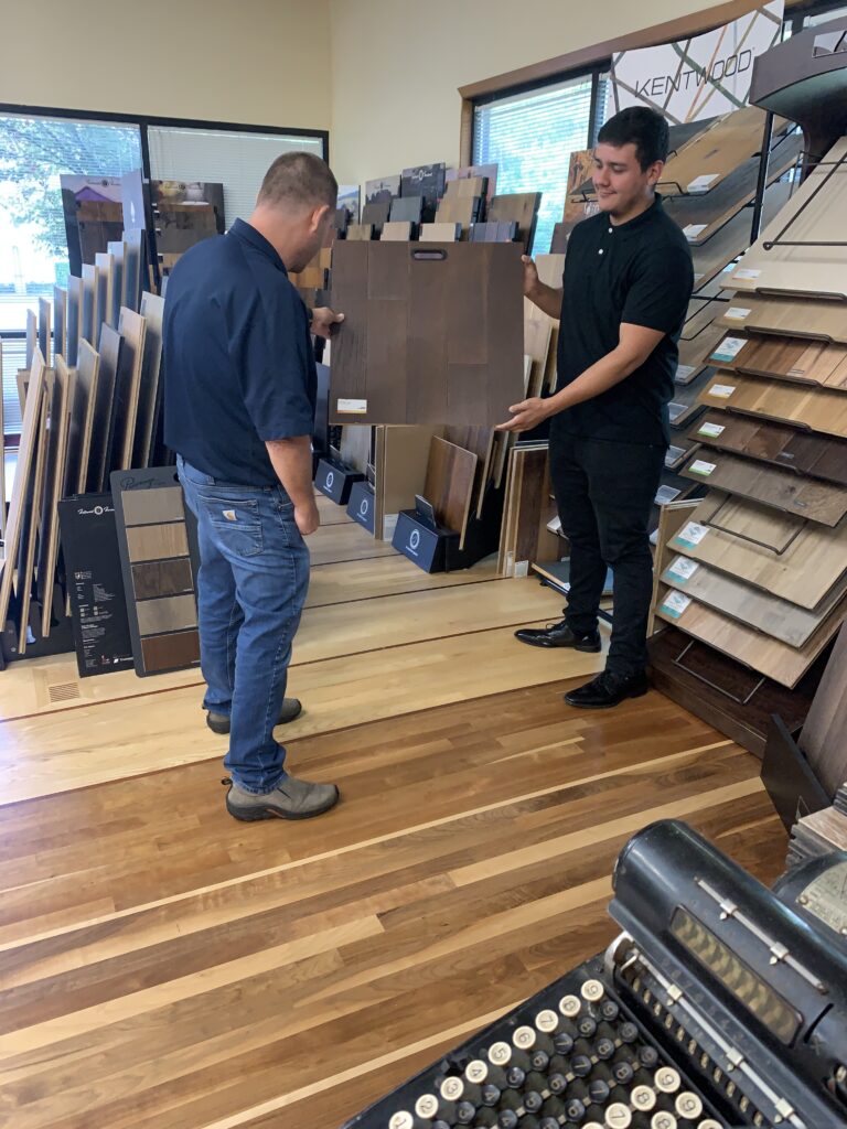 The team carrying a flooring sample inside the store. Flooring pacific northwest. Craftcore Flooring Solutions